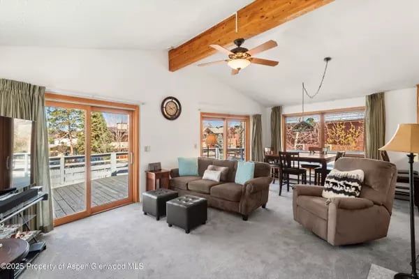 Living room with an exposed wood ceiling beam and sliding glass doors opening to a deck.