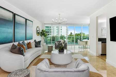 Contemporary condo living room with curved white sofa and floor-to-ceiling windows overlooking greenery.