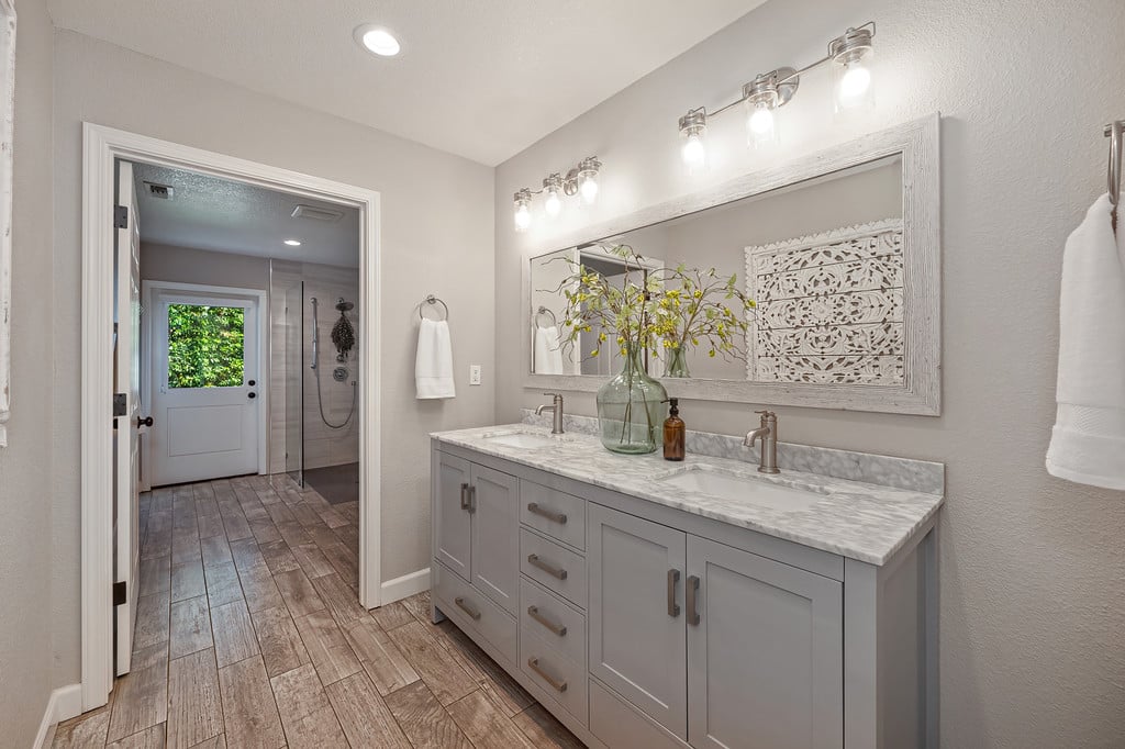 Bathroom with a gray double vanity and large mirror, opening to a walk-in shower.