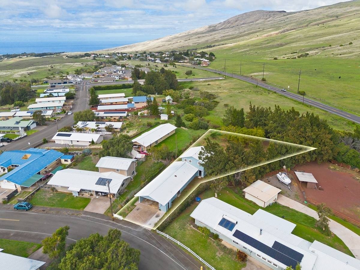 Aerial view of a Waimea home and outlined property beneath green hills near the coast.