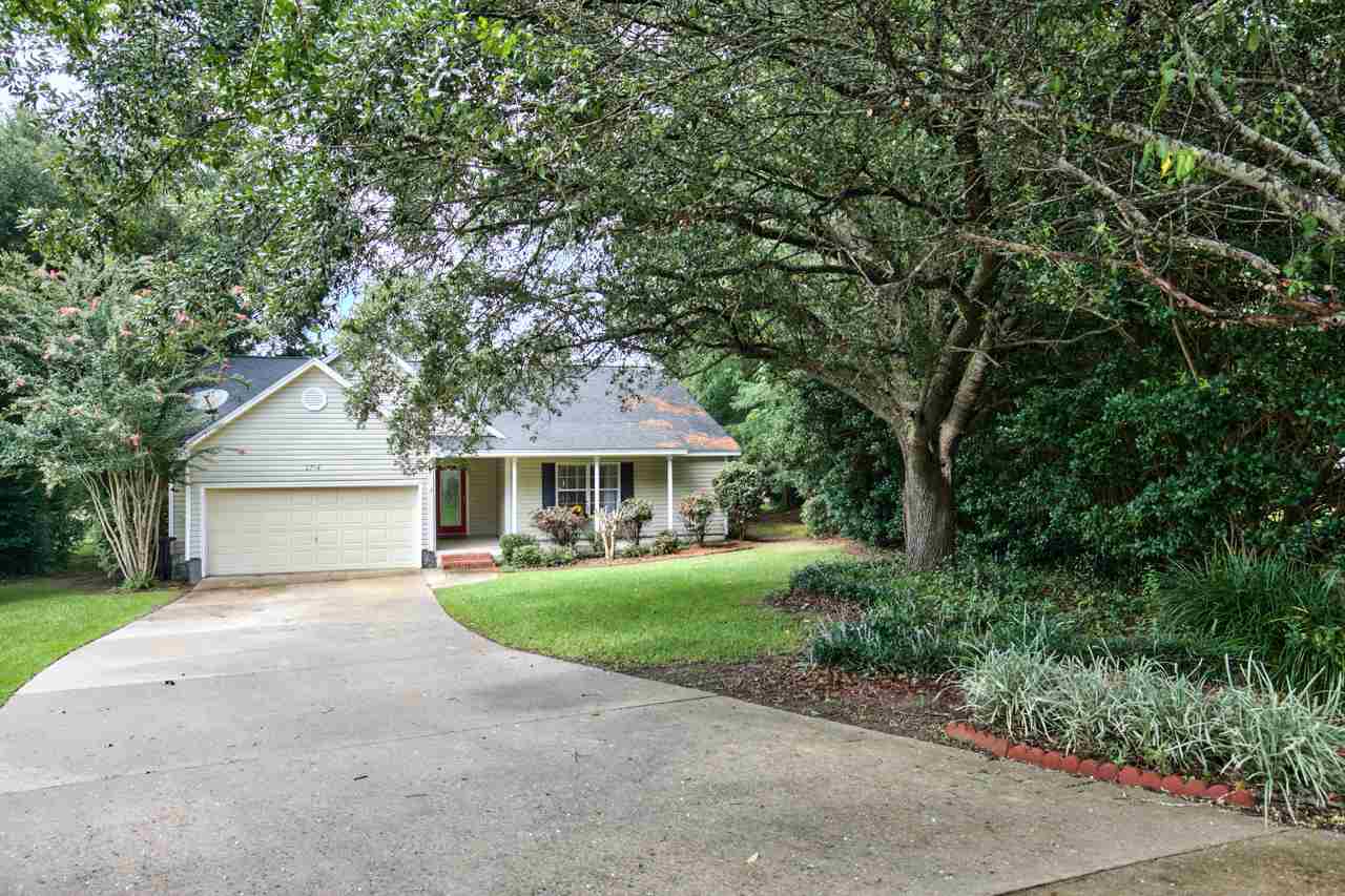 A house with a driveway surrounded by trees in the yard, showcasing a serene residential environment.