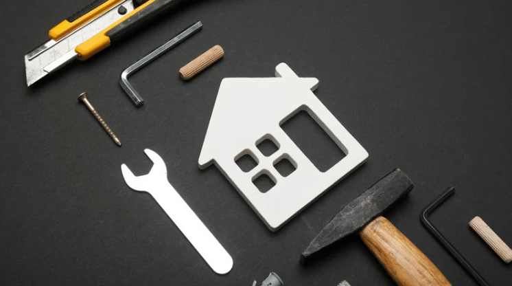 House-shaped cutout surrounded by renovation tools, including a wrench, hammer, and utility knife.