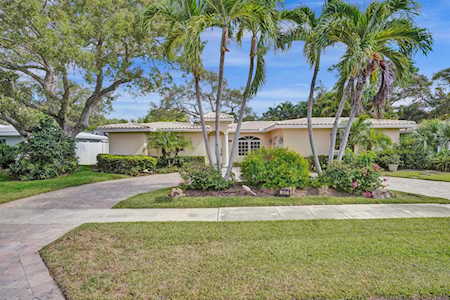 Single-story home with a curved driveway, front lawn, and palm trees.