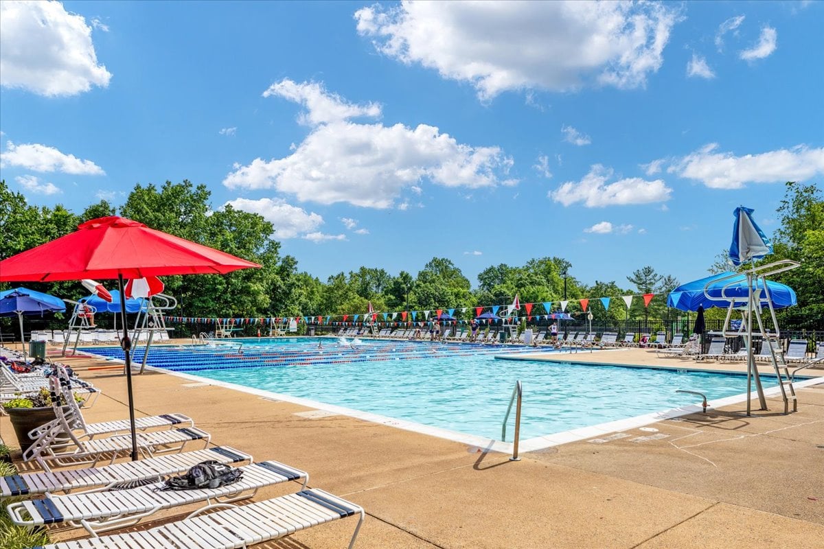 Outdoor pool with lap lanes, lounge chairs, and bright umbrellas along the deck.