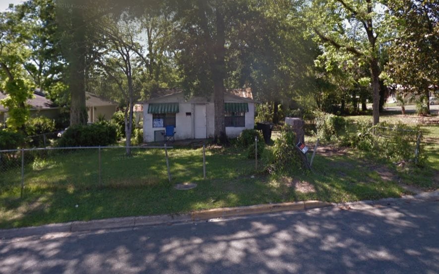 A house surrounded by a fence and trees, showcasing a serene yard setting.