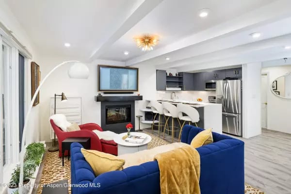 Open-plan living room with blue and red sofas, fireplace, and kitchen island.