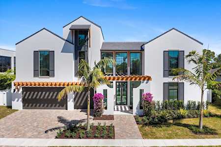 Modern two-story white home with a geometric facade, two-car garage, and landscaped palms.
