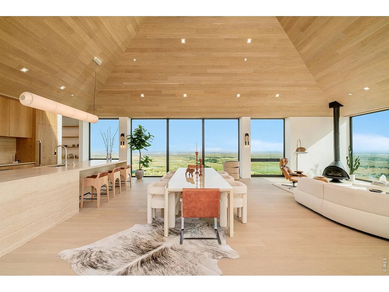 Open-plan dining and living area with a wood ceiling and expansive countryside views.