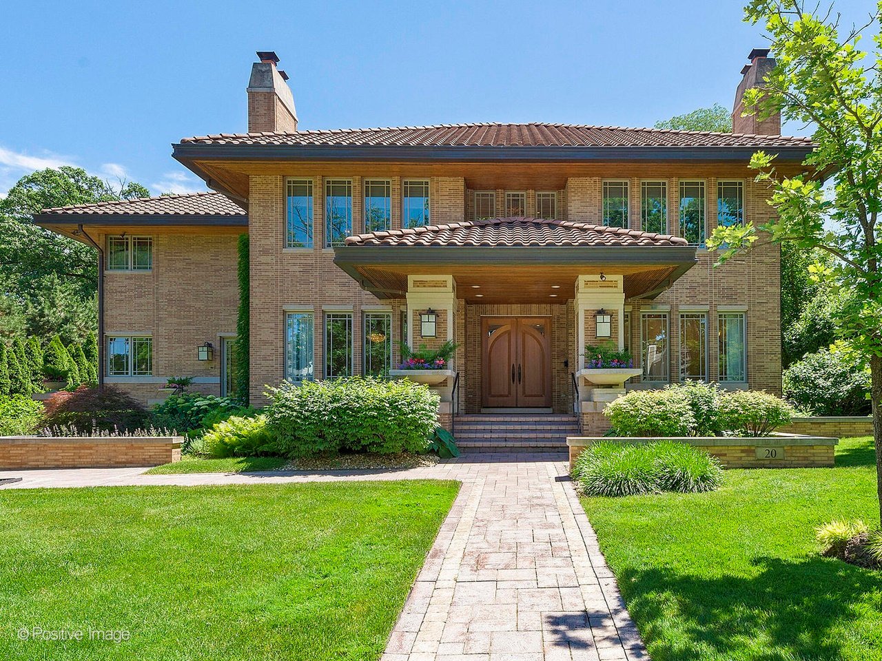 Two-story brick house with a tiled roof, covered entrance, and landscaped lawn.