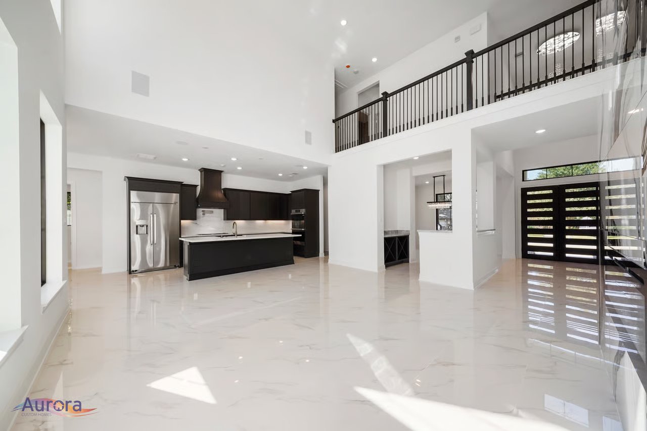 Open-plan kitchen with dark cabinetry, a large island, glossy floors, and an upstairs gallery railing.