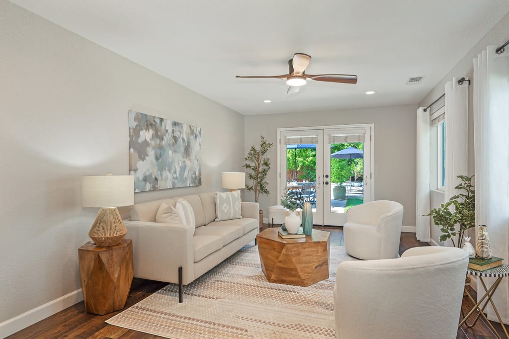 Living room with cream seating, a geometric wood coffee table, and glass doors to the backyard.