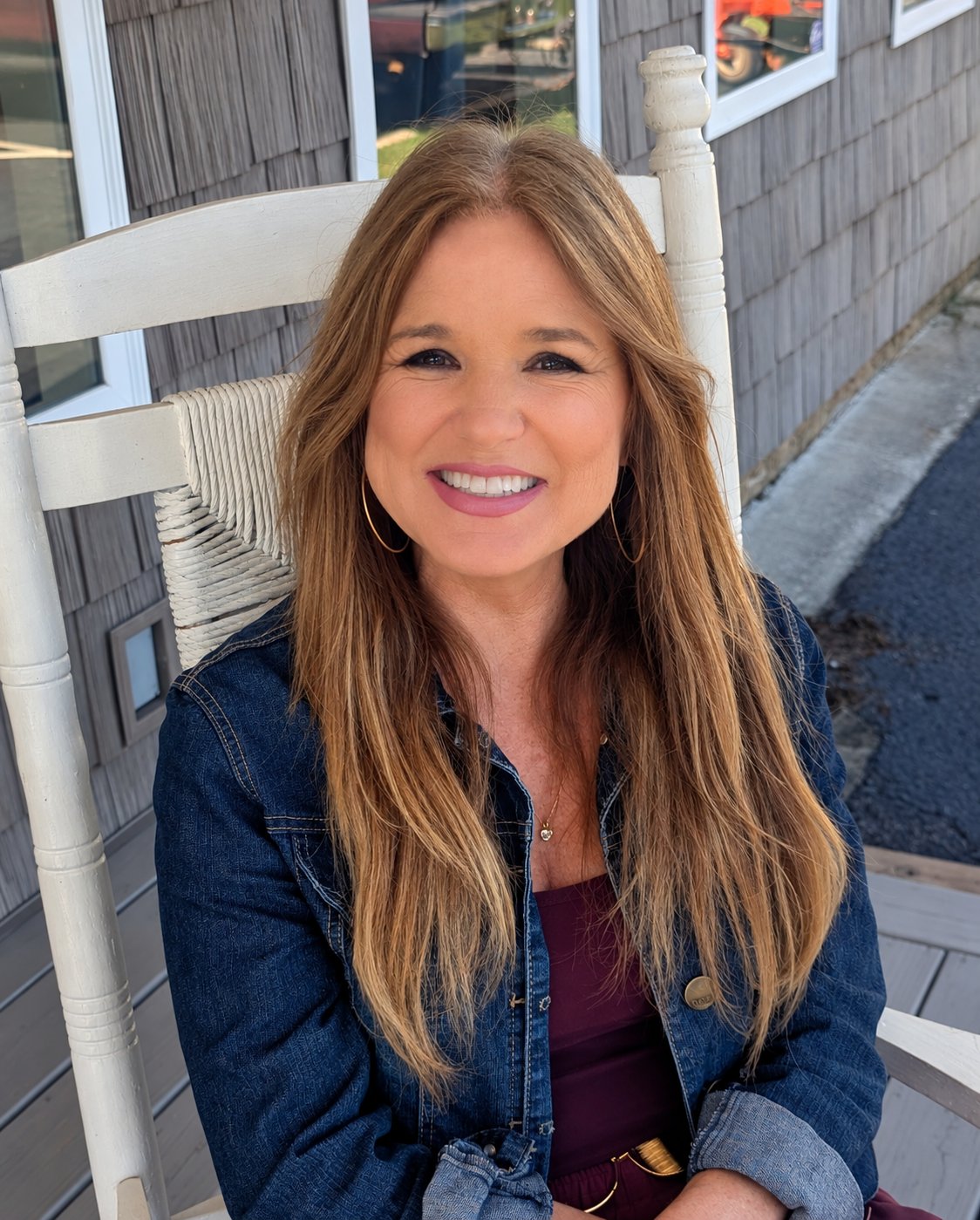 Tonya Smith smiling in a white porch chair, wearing a denim jacket and hoop earrings.