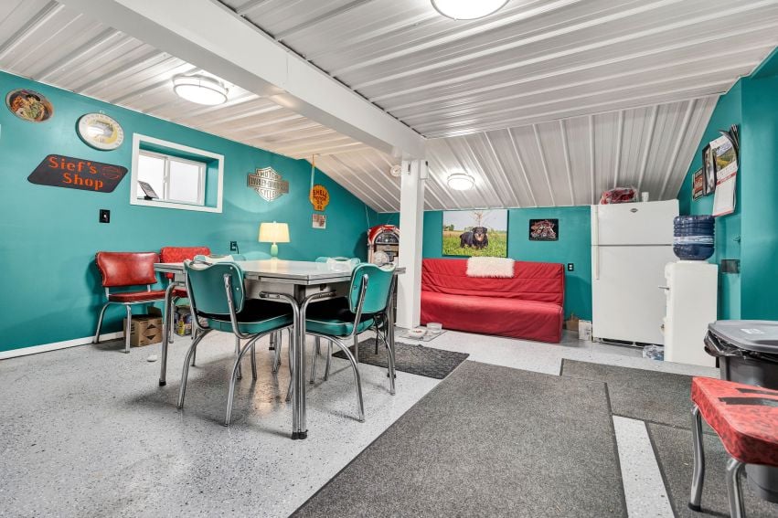 Turquoise-walled room with a metal dining set, red bench, refrigerator, and water cooler.