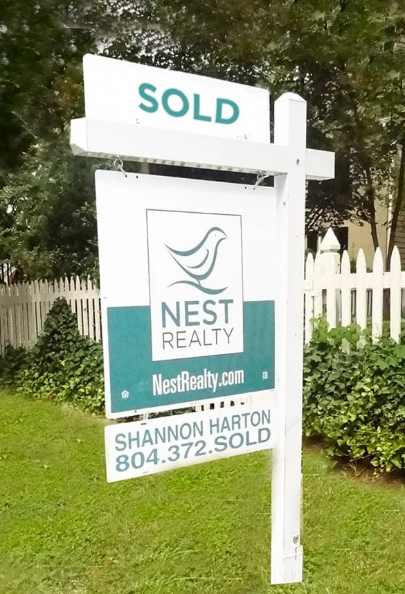 Sold real estate sign for Nest Realty agent Shannon Harton on a lawn.