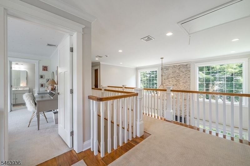 Bright upstairs landing with white railings, large windows, and an adjoining home office.
