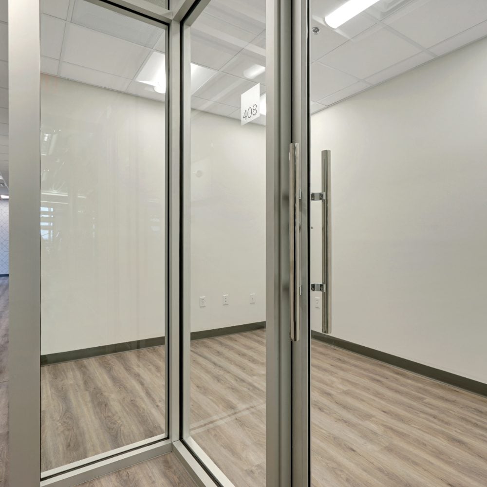 Empty office suite behind glass doors, with wood-look flooring and a hanging 408 sign.