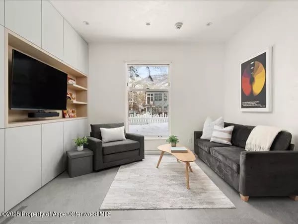 Living room with built-in television cabinetry, gray seating, and a large window.