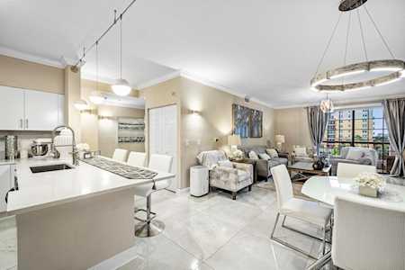 Open-plan condo kitchen and living area with a white island, neutral furnishings, and large windows.