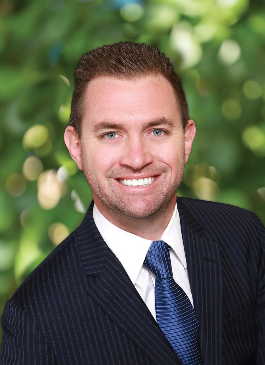 Christopher Holmes smiling in a navy pinstripe suit and blue tie.