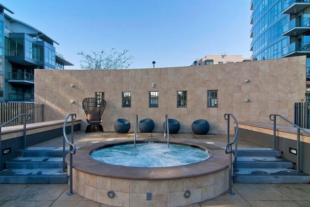 A large, circular outdoor hot tub on a tiled patio at the Madrone, with steps and handrails for easy access.