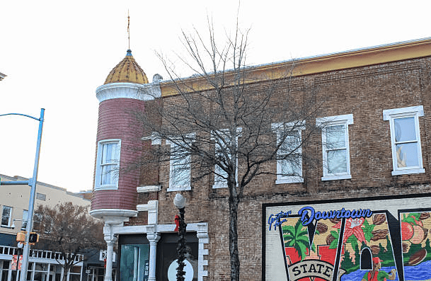 Downtown streetscape with a brick building, rounded tower, and colorful mural.