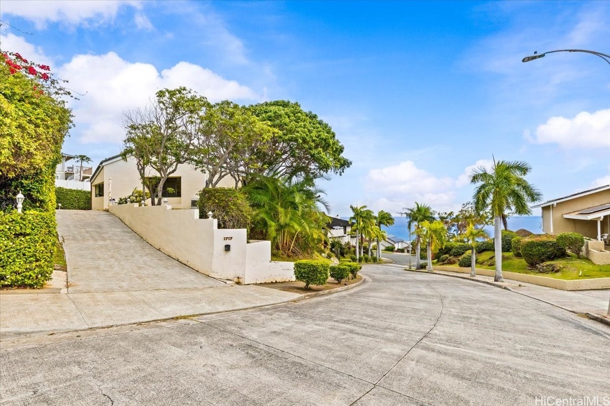 1717 Palaau St home above a sloped driveway, with tropical landscaping and an ocean view.