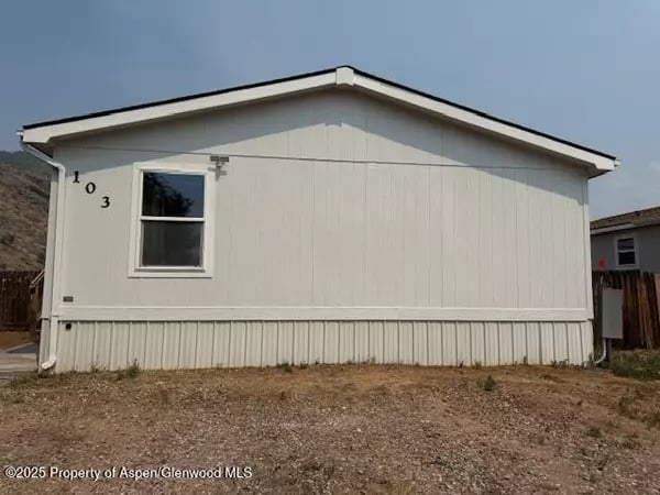 White manufactured home with a single window and the number 103 on its side.
