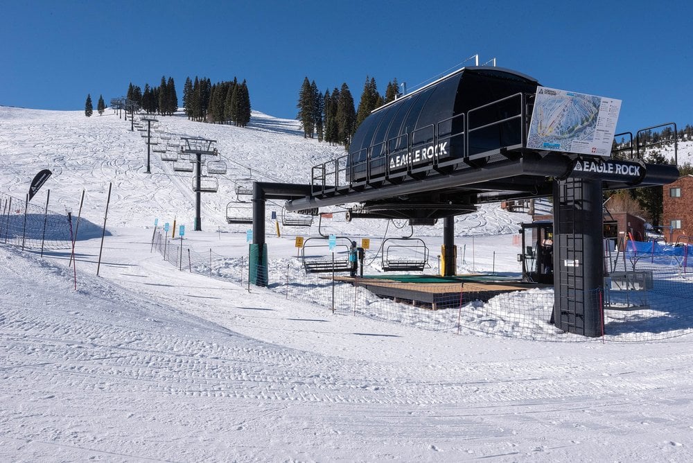 Eagle Rock ski lift station beside a snow-covered slope and evergreen trees.