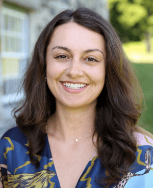 Corinne Singer smiling in a blue patterned blouse outdoors.