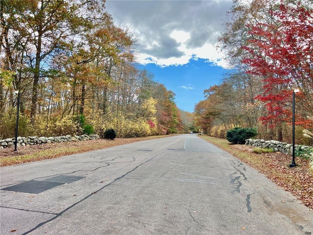 Quiet road lined with autumn trees and stone walls.