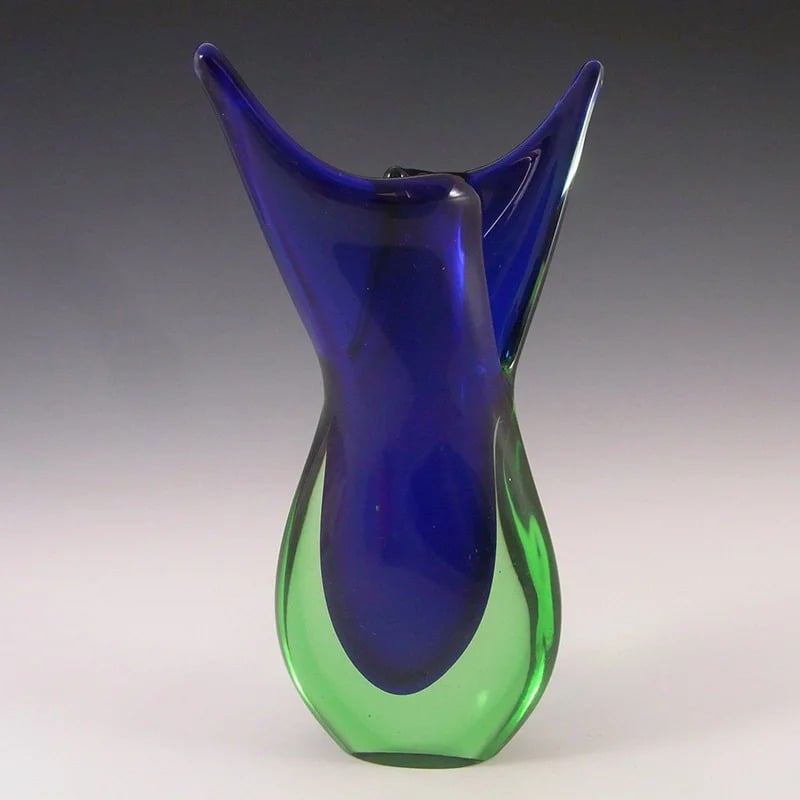 Sculptural glass vase with a cobalt-blue center, translucent green body, and flared, pointed rim.