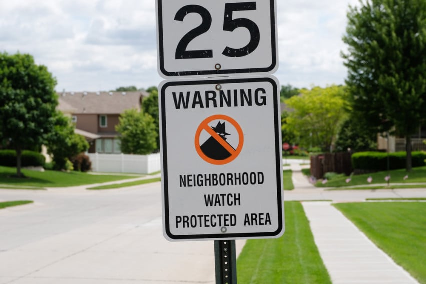 Neighborhood street with a 25 mph sign and neighborhood watch warning.