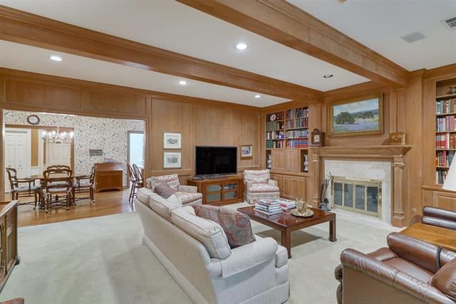 Living room with wood-paneled walls, ceiling beams, built-in bookshelves, and a fireplace.