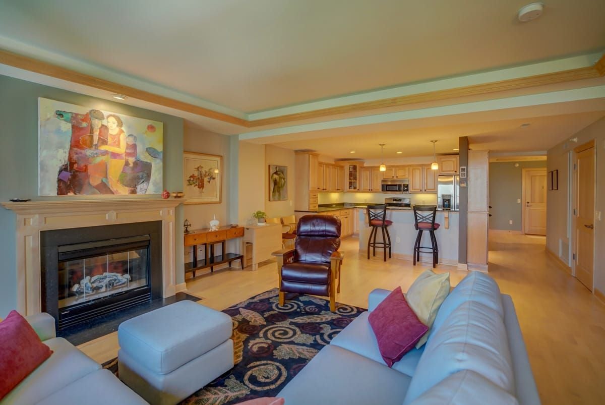 Living room with fireplace, colorful artwork, and open kitchen with breakfast bar.