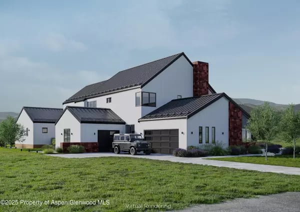 Modern white home with dark metal roofs, stone chimney accents, and a vehicle in the driveway.