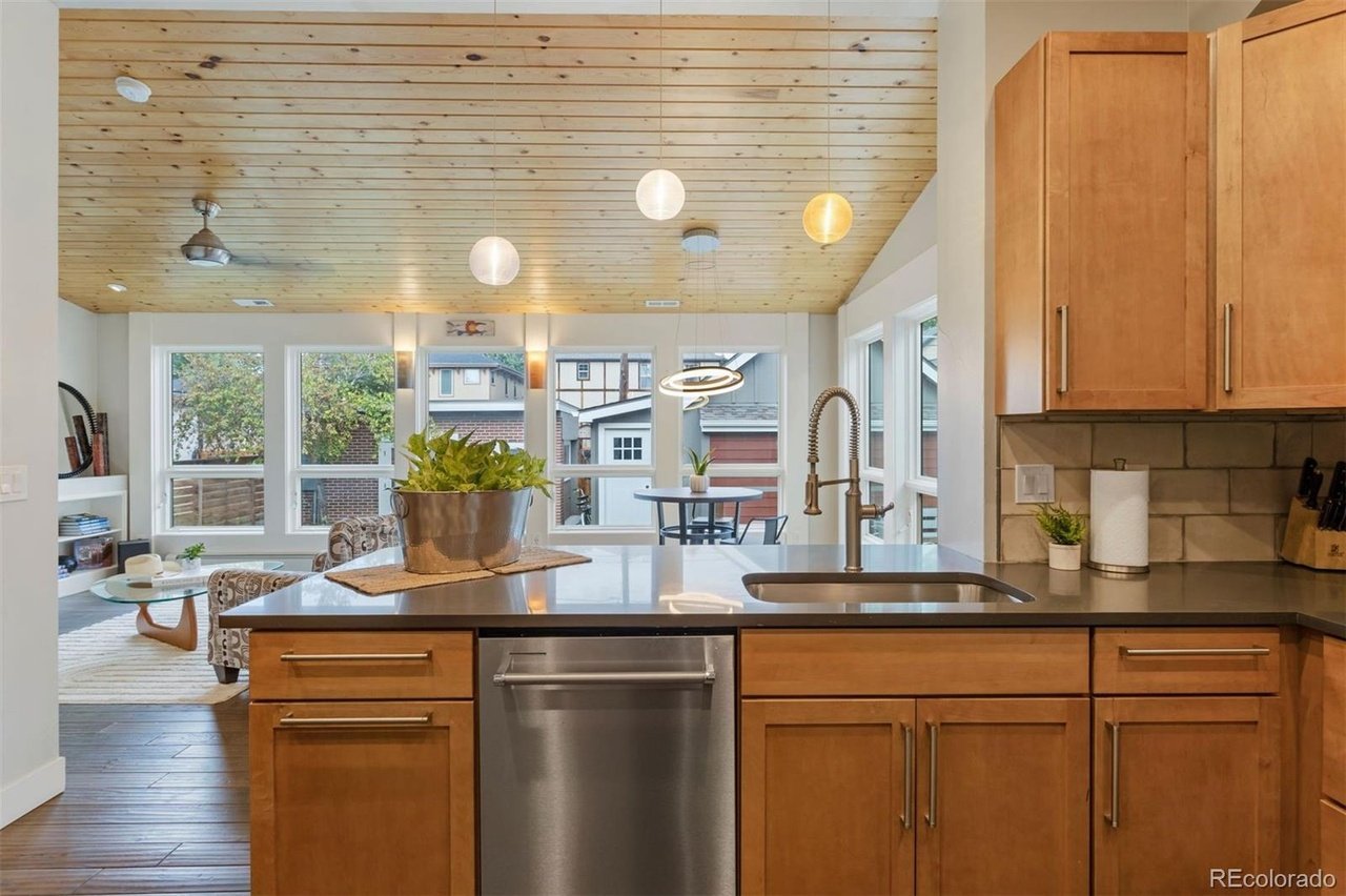 Kitchen with warm wood cabinets, a large island sink, and a distinctive wood-plank ceiling.