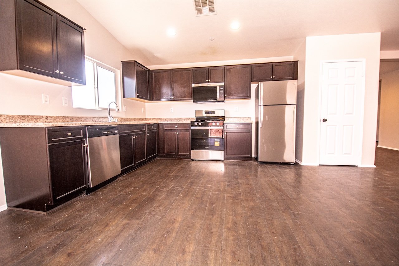 Vacant kitchen with dark cabinets, granite counters, and stainless steel appliances.