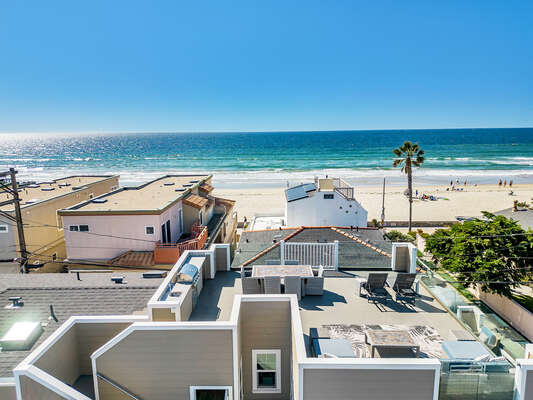 Aerial view looking west from the Mission Bay side over waterfront homes in Mission Beach toward the Pacific Ocean, showcasing the unique peninsula lifestyle that makes this San Diego beach community so iconic.