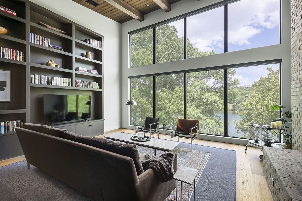 Living room with 12.5-foot built-in bookshelves and a wall of windows to Lake Austin, furnished by Liz MacPhail Interiors. Designed by Kelley Design Group, built by Pecan Valley Custom Homes. Lake Austin waterfront at 2403 Big Horn Drive, Austin.