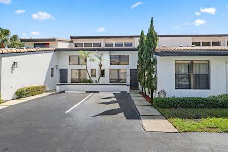 Low-rise residential building with a paved parking area and tall evergreen beside the walkway.