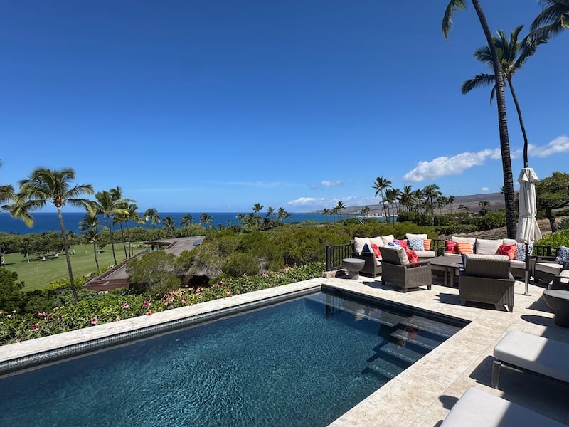 Swimming pool and furnished terrace overlooking the ocean, palms, and a golf course.