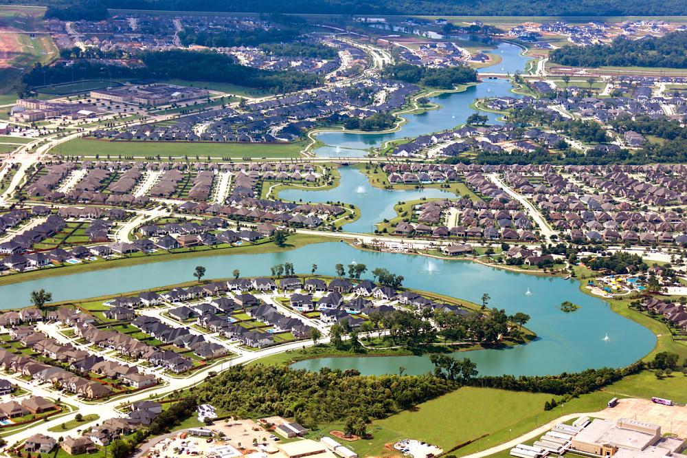 Aerial view of homes lining interconnected lakes and green spaces.