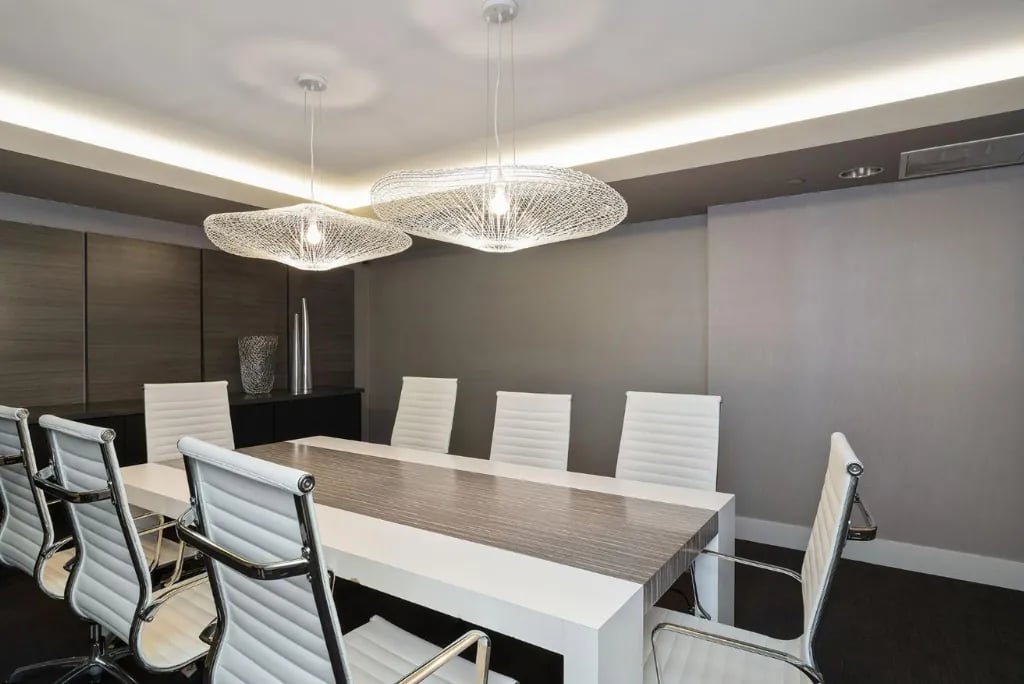 Modern conference room at Madrone San Francisco with sleek pendant lighting, wood grain table, white leather chairs, and contemporary gray interior design