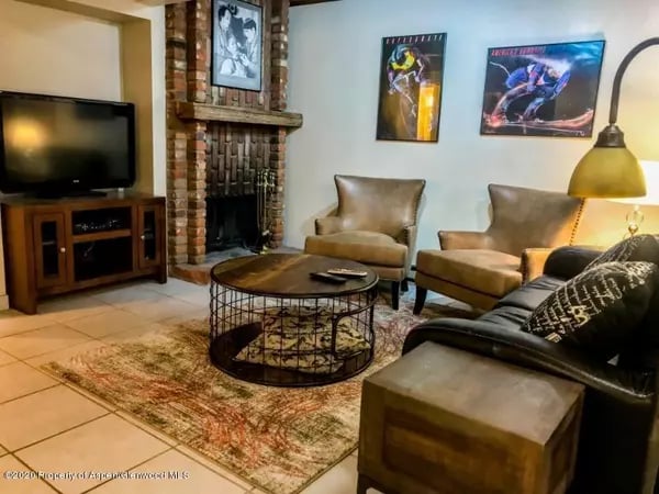 Living room with a brick fireplace, leather seating, and a round metal coffee table.