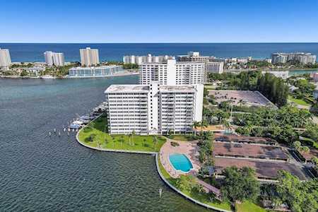 Waterfront condominium buildings beside an inlet, with a pool and ocean coastline beyond.