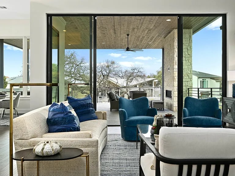 Furnished living room with a cream sofa and blue armchairs beside sliding doors to a covered patio.