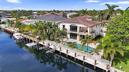 Waterfront home with a private dock, swimming pool, and palm-lined canal.
