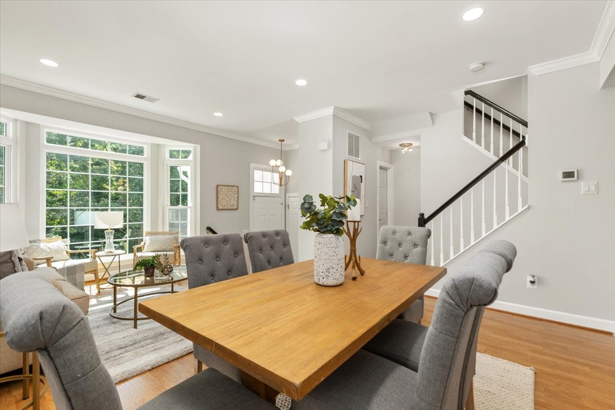 Dining area with a large wooden table beside a bright living room and tall grid-pane windows.