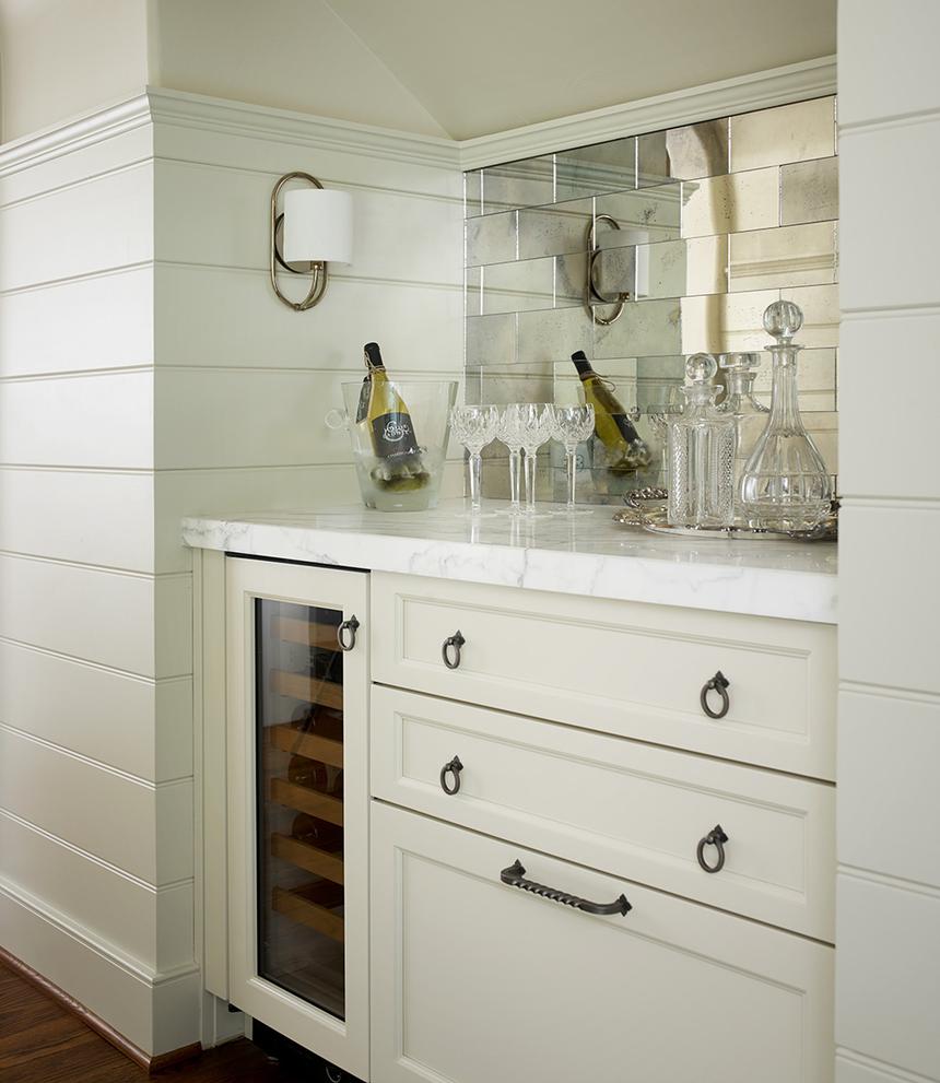 Built-in bar with a wine refrigerator, marble counter, champagne, and crystal glassware.