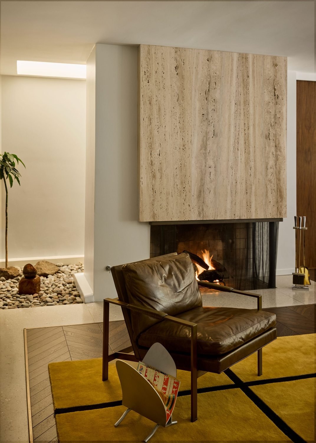 Sitting area with a stone fireplace, travertine surround, and a single leather chair.